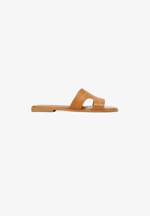 Tan leather slide sandals with an open toe design, flat sole, and two wide straps featuring a cutout detail. Smooth texture.