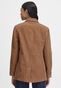 Brown corduroy blazer with a notched collar, long sleeves, and a straight cut. Features vertical ribbed texture and a back vent.