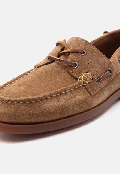 Καφέ καστόρινο μοκασίνι ανδρικό με δερμάτινες κορδόνια και ραμμένη μύτη, εμφανίζεται σε λευκό φόντο.