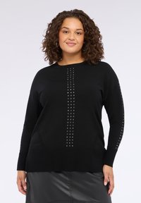Maglioncino nero in maglia con texture a costine, maniche allungate e borchie argento disposte sul davanti e lungo le maniche.