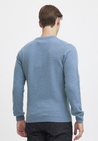 Light blue knitted sweater with long sleeves, round neckline, and ribbed cuffs and hem. Made from soft, textured fabric.