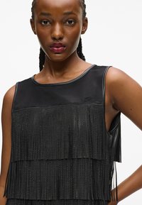 Fekete rojtos ruha, réteges textúrával, fémes akcentusokkal és sima selyem felső résszel. Kerek nyakú és ujjatlan kivitel.