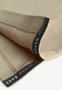 Beige bomuldsstof foldet med sort label-stikning, der inkluderer "TED BAKER." Glat tekstur med en subtil glans.
