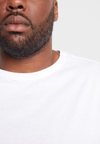 Witte katoenen T-shirt met een ronde hals. Toont een gladde textuur en een eenvoudig, onopgesmukt ontwerp. Close-up van de kraag.