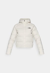 Hvit puffjakke med hette, med glidelås foran og sidelommer. Stoffet har en glatt tekstur med et sydd mønster.
