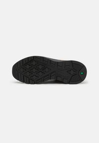 Czarna, gumowa podeszwa z wzorowanym bieżnikiem, z logo Timberland i zielonym akcentem na pięcie. Wytrzymała i teksturowana konstrukcja.