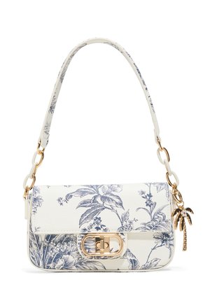 Bolso blanco con estampado floral azul, cierre dorado, adornos de eslabones blancos y un charm dorado de palmera en la correa.