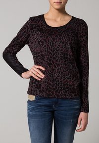 Top de manga larga en un patrón rojo oscuro y negro, con un cuello redondo y mangas con textura en contraste. Fabricado en una suave tela elástica.
