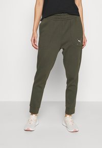 Grüne, schmal zulaufende Jogginghosen mit einem elastischen Bund, ausgestattet mit zwei Fronttaschen und einem kleinen Logo auf der linken Tasche.