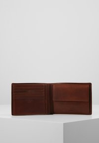 Bruine leren portemonnee met meerdere kaartsleuven en een voorkTF. De portemonnee heeft een gladde textuur en een minimalistisch ontwerp.