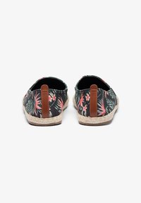 Espadrilles with black fabric featuring pink floral and green tropical patterns. Jute soles with brown leather accents at the heel.