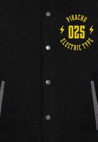 Sort varsity-jakke med sølvtryknapper og grå detaljer. Har et gult grafisk print: "Pikachu 025 Elektrisk Type."