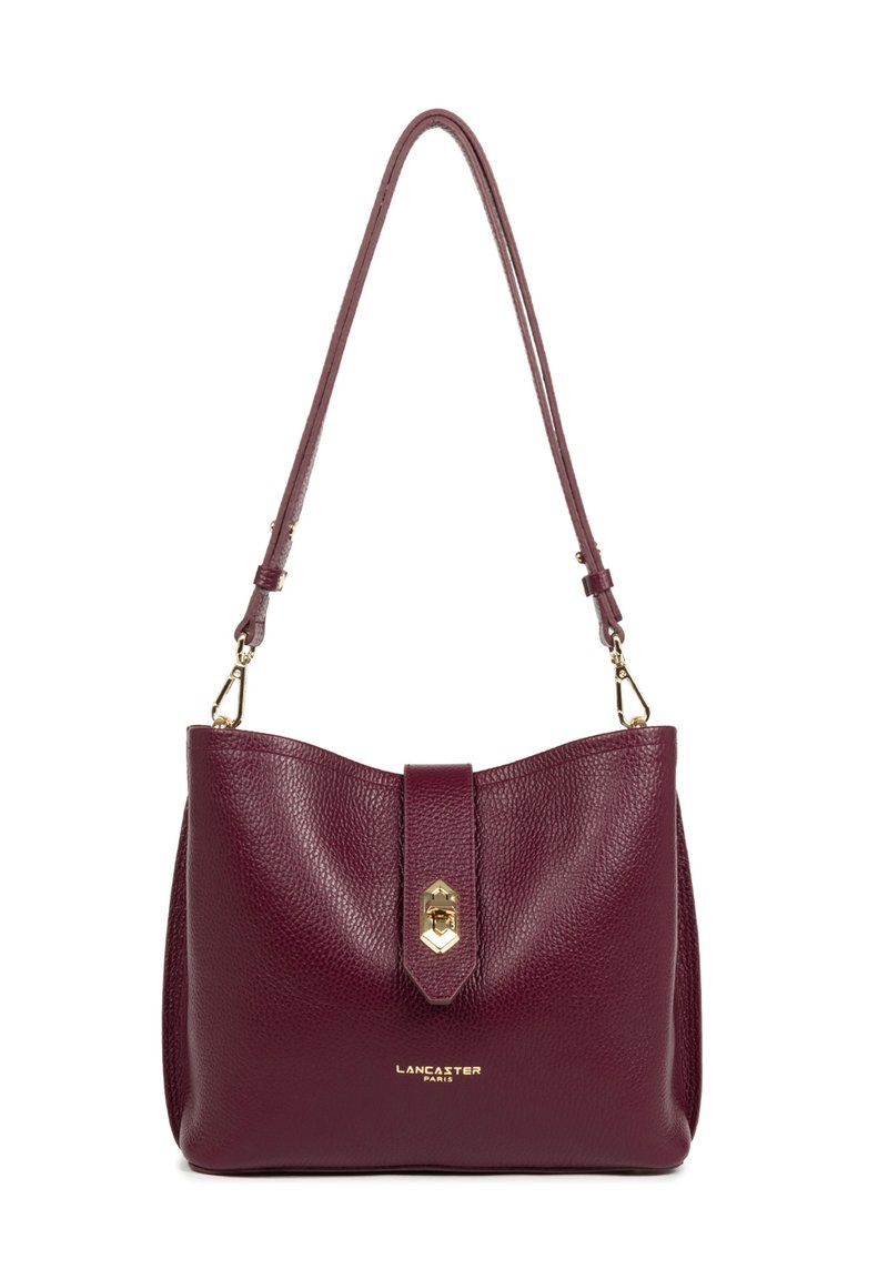 Sac à main en cuir bordeaux avec une finition texturée, dotée d'une fermeture en métal doré et d'une sangle réglable, présentant un design minimaliste.