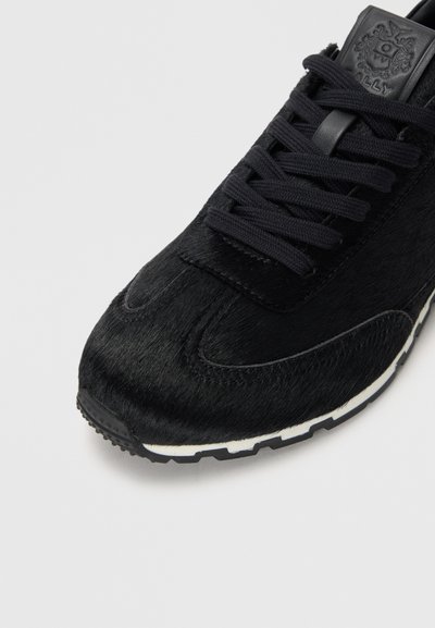 Sneaker noir avec une tige en fourrure texturée, lacets noirs et semelle en caoutchouc blanche. Présente un logo discret sur la languette et un design de bout rond.