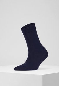 Granatowa skarpetka do kostki z ribbowanym mankietem, gładką teksturą i dopasowanym kształtem. Wykonana z rozciągliwego materiału dla wygody i trwałości.