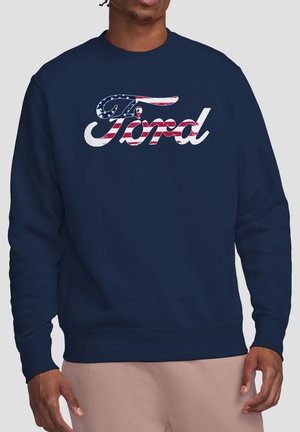Man wearing navy blue sweatshirt with the word Ford in a distressed American flag pattern across the chest.