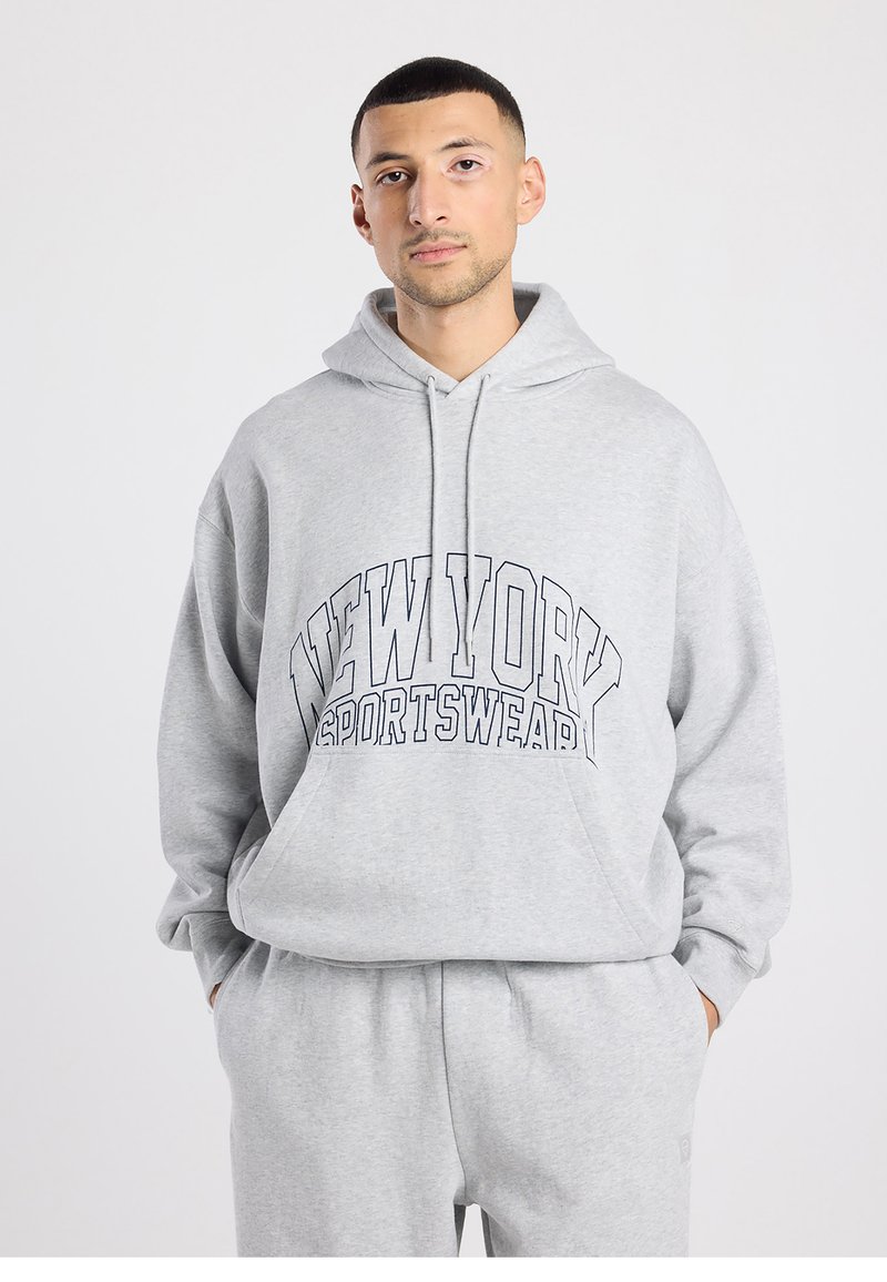 Grijze hoodie gemaakt van zacht materiaal met een voorkantzak. Heeft de tekst "NEW YORK SPORTSWEAR" in dikke zwarte letters op de borst.