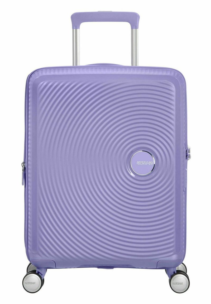 Valigia rigida di colore lavanda, con un motivo a onde testurizzate, logo argentato, manico telescopico e quattro ruote girevoli multicolori.