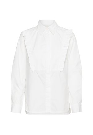 Valge puuvillane särk, millel on volangdetailid õlgadel, pikad varrukad ja nööbiga esiosa. Üksikasjalik lõige, millel on klassikaline krae.