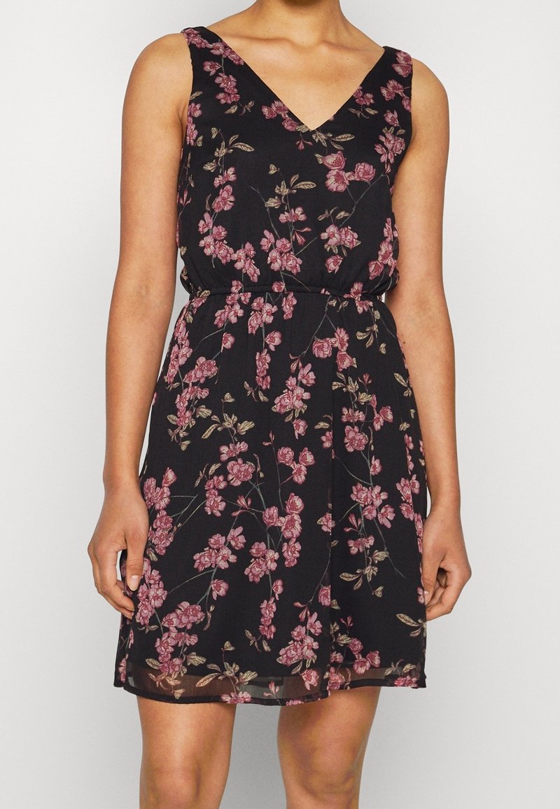 Schwarzes Blumenkleid mit V-Ausschnitt, das mit rosa und beigen Blumenmustern verziert ist, einer taillierten Taille und einer fließenden Silhouette.