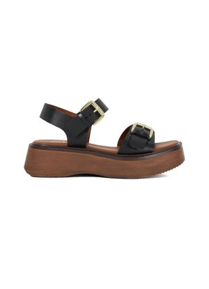 Sandales à plateforme en cuir noir avec deux accents en boucle dorée, semelle en bois brun, design à bout ouvert et brides de cheville ajustables.