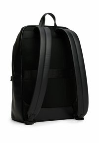 Sac à dos noir au design épuré, en cuir lisse, avec un dos en maille matelassée et des bretelles réglables pour un confort et un soutien accrus.