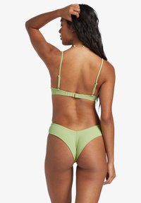 Bikini verde a coste con spalline regolabili e chiusura sul retro. La parte inferiore presenta un taglio a V, che valorizza il design testurizzato.