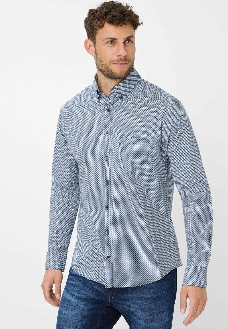 Camicia abbottonata caratterizzata da un motivo geometrico blu e bianco, realizzata in tessuto di cotone, con maniche lunghe e collo con bottoni decorativi.