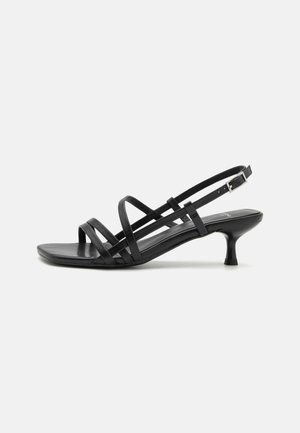 Black heeled sandals with multiple crisscross straps. Smooth material, pointed toe, and narrow heel. Adjustable ankle strap with buckle.