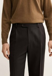 Pantaloni neri su misura con una texture liscia, caratterizzati da un davanti piatto, due tasche e una chiusura con bottone in vita.