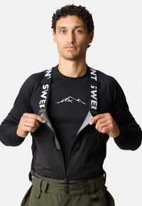 Zwarte rits buitenlaag met groene broek, verstelbare banden en een bergontwerp op het zwarte shirt daaronder. Gestructureerde stof.