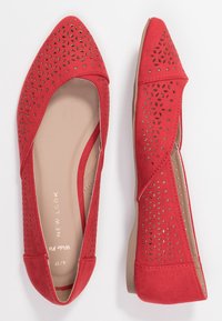 Červené semišové baleríny s špičatou špičkou, zdobené výřezy, měkkým vnitřkem a hladkou béžovou podrážkou.