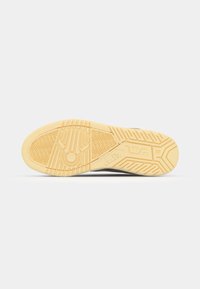 Sneaker sole with textured rubber in beige, featuring a patterned tread design for traction and durability. Manufacturer branding is subtle.