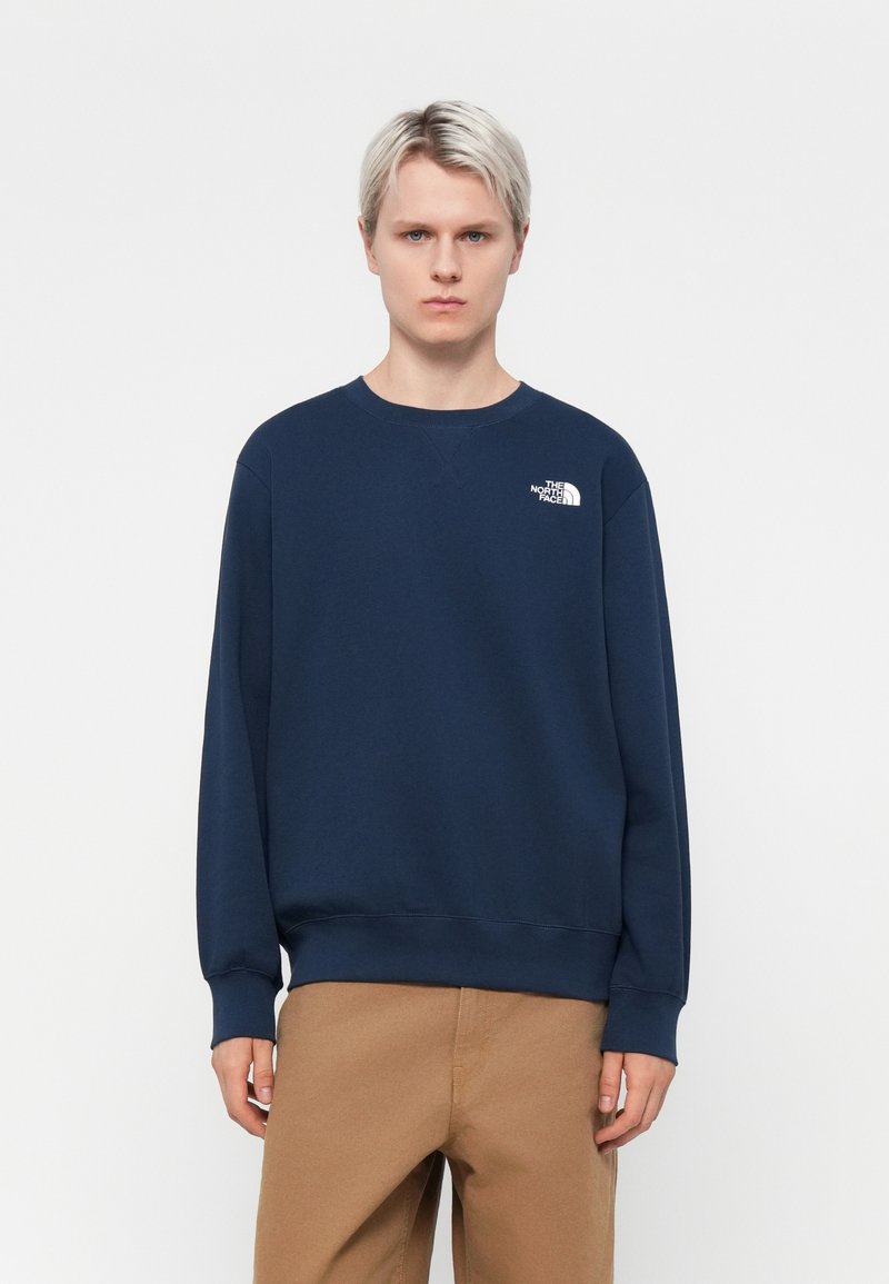 Navy blue sweatshirt with a crew neck, ribbed cuffs, and hem. Features a white logo on the left chest. Made of cotton blend material.