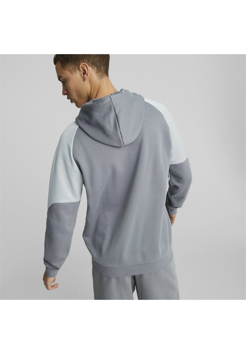 Felpa grigia con cappuccio e accenti grigi chiari, polsini a coste e finitura testurizzata, vista da dietro. Design minimalista, vestibilità rilassata.