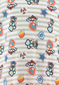 Camisa blanca con rayas grises, que presenta coloridos personajes de dibujos animados e íconos como huellas de patas, estrellas y escudos en varios colores.