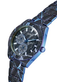 Reloj Guess con pulsera de patrón de mármol negro y azul, caja de acero inoxidable, esfera redonda, cara negra, marcadores de hora plateados y sub-esferas de cronógrafo dual.