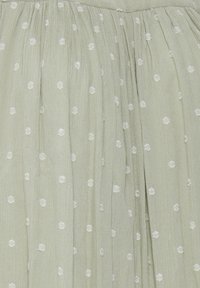 Falda de tejido plisado verde con puntos florales bordados en blanco en todo su diseño, con una textura suave y un diseño ligero.