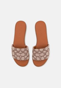 Paire de sandales slides en cuir marron avec des brides en tissu à motif tissé beige et marron, semelle plate, et nom de marque embossé sur la semelle.