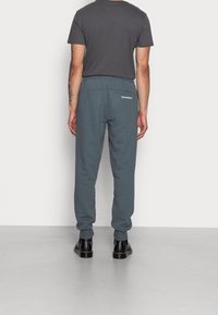 Grau melierte Baumwolljogger mit lockerem Schnitt, elastischem Bund und gerippten Bündchen. Verfügt über ein kleines weißes Logo auf der Gesäßtasche.