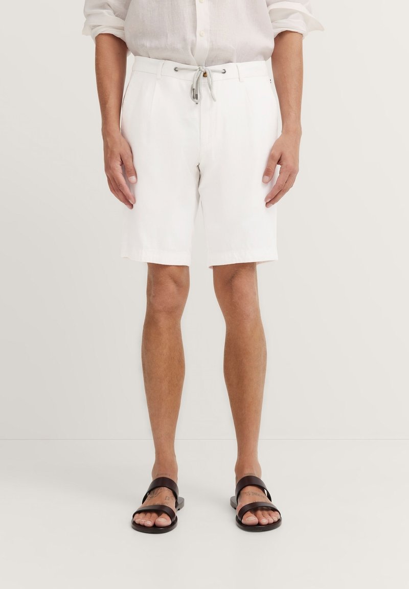White cotton shorts with a drawstring waist, featuring side pockets and a straight cut, paired with dark brown sandals.