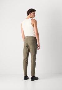 Heren slim-fit, olijfgroene broek met een elastische tailleband, gladde textuur en achterzak. Draag met een witte tanktop en zwarte schoenen.