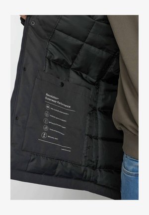 Zwarte pufferjas binnenkant met doorgestikte textuur. Bevat een label met gedetailleerde materiaalspecificaties; inclusief waterdicht weefsel en SBS-rits.