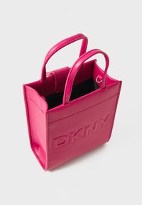 Borsa tote in pelle rosa con logo "DKNY" impresso, manici doppi arrotondati, apertura superiore e forma quadrata. Texture liscia, design minimalista.