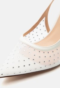 Λευκό μυτερό γοβάκι με διάφανα panel και σκορπισμένες μικρές ασημένιες στρας.