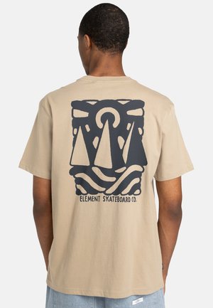 Beige cotton t-shirt featuring a large black graphic of two triangular shapes and wavy lines, with "Element Skateboard Co." text underneath.