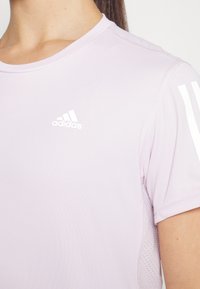 Ljuslila Adidas sportströja med rund hals, korta ärmar och vita tre-randsaccenter på axlarna.