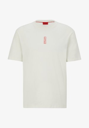 T-shirt blanc à manches courtes avec un col rond, présentant un petit logo vertical rouge "HUGO" au centre de la poitrine.