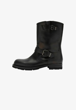 Schwarze Leder-Ankle-Boots mit runder Zehenpartie, verstellbarem Schnallenriemen und strukturiertem Obermaterial. Mit einer stabilen Sohle mit Profil.