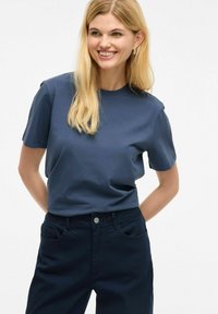 Camiseta de manga corta azul marino en una tela suave, con un escote redondo. Combinada con pantalones azul marino oscuros con bolsillos frontales y un botón.